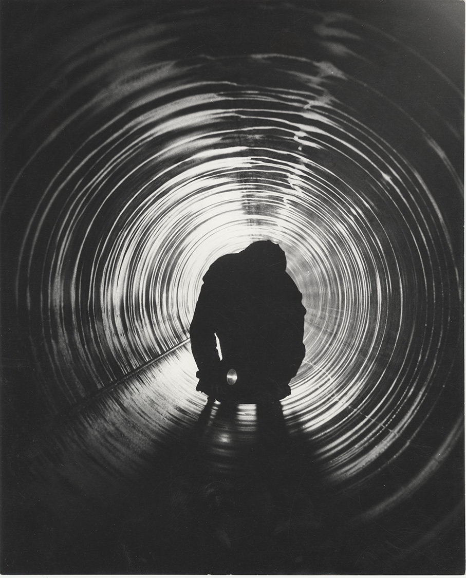 Operaio durante un controllo di qualità all’interno di un tubo nello stabilimento Italsider di Taranto, 1963